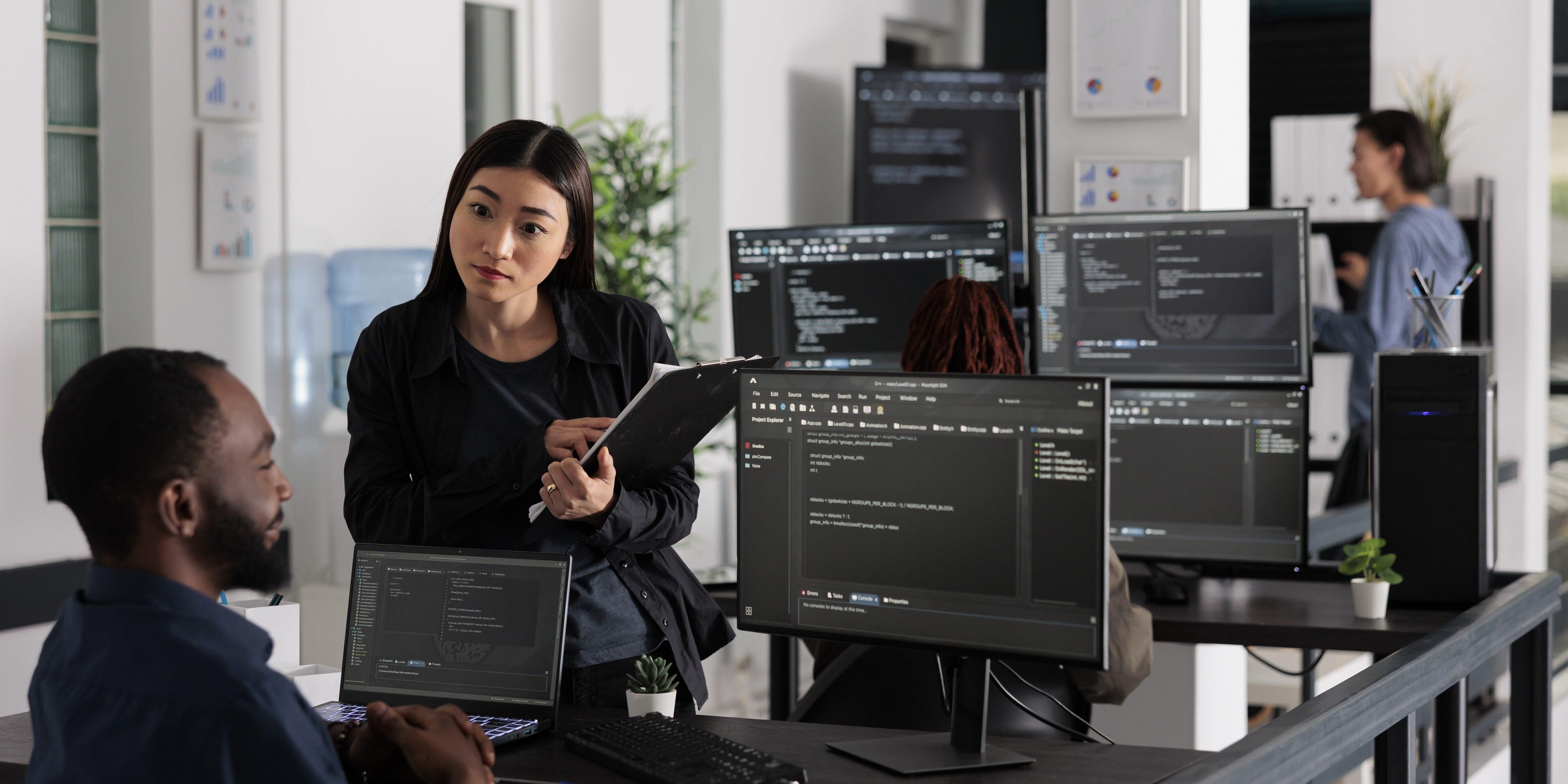 A woman and man collaborate on a computer in a modern office setting, focused on their work.